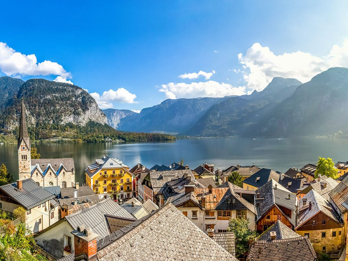 Malerisches Dorf Hallstatt in Österreich mit Kirche, See und majestätischen Bergen unter blauem Himmel.