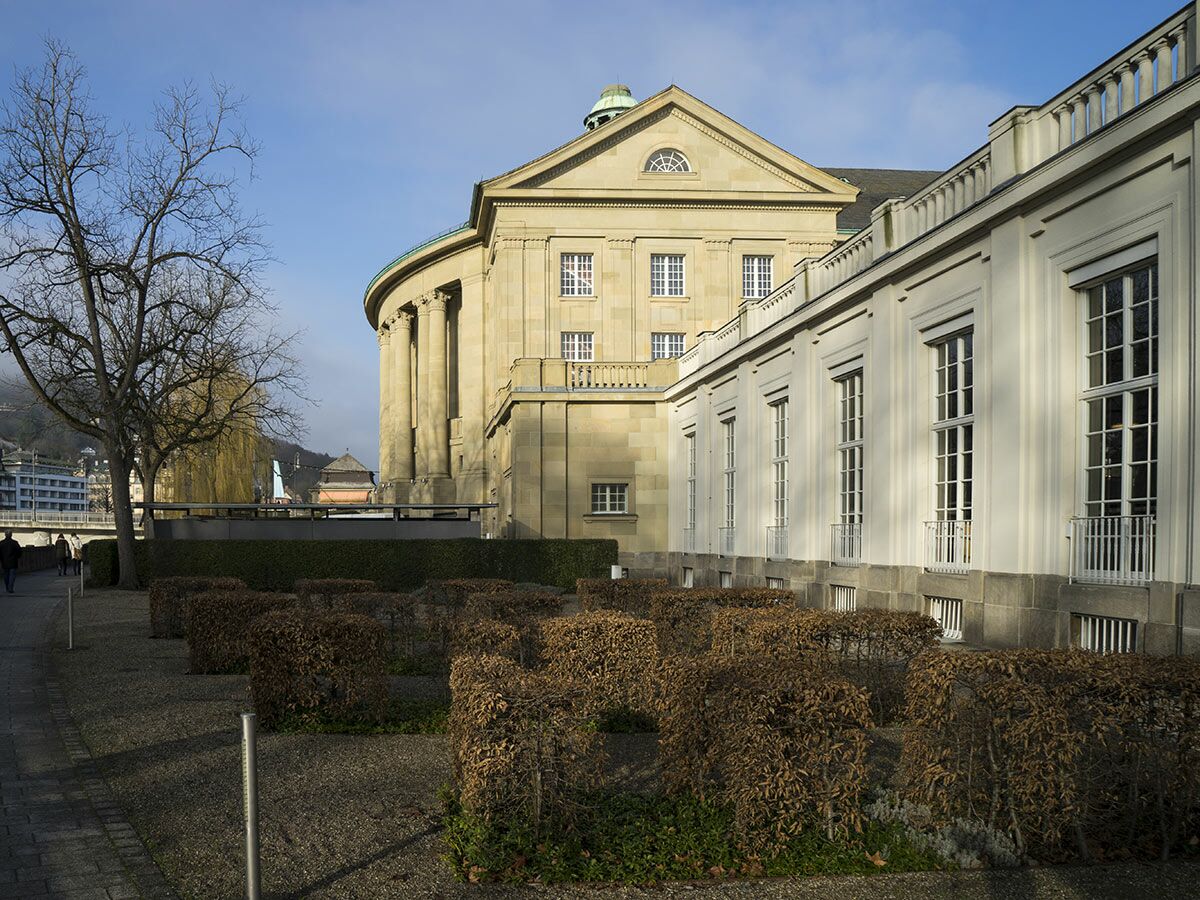 Stattliches Gebäude der Liederhalle Stuttgart mit klassischen Säulen, großen Fenstern, gepflegtem Park und kahlen Bäumen im Winter.