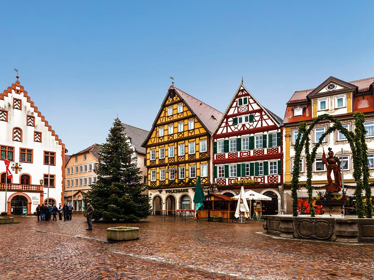 Ein festlich geschmückter historischer Marktplatz mit Fachwerkhäusern, Weihnachtsbaum und Brunnen in einer deutschen Stadt.