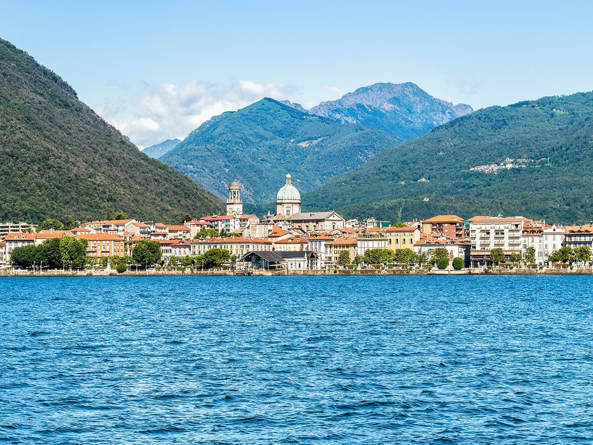 Panoramablick auf die Stadt Lugano am Luganersee mit historischen Gebäuden, Kuppelkirche und grünen Bergen.