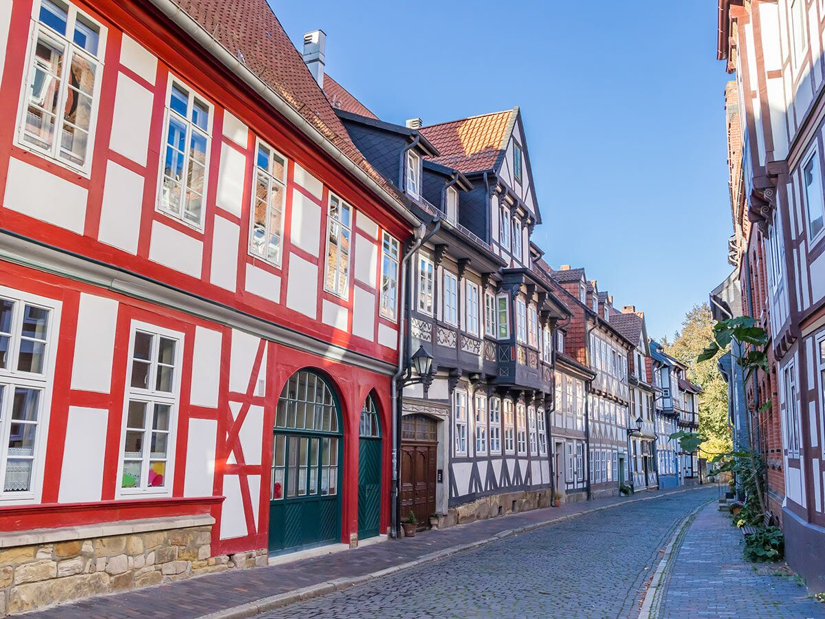 Idyllische Kopfsteinpflasterstraße mit traditionellen roten und weißen Fachwerkhäusern in einer historischen deutschen Altstadt unter blauem Himmel.