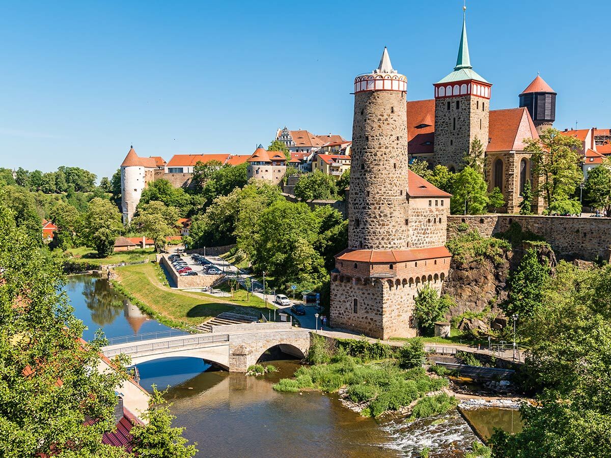 Historische Altstadt Bautzen, Sachsen, mit Petridom, Reichenturm, Fluss Spree, Brücken und grünen Bäumen an sonnigem Tag.