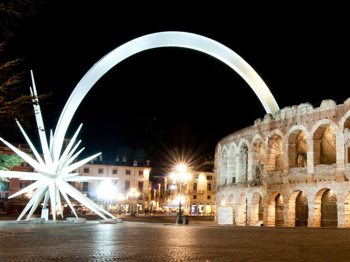 Nachtaufnahme der beleuchteten Arena von Verona und dem riesigen Weihnachtsstern auf der Piazza Bra in Italien.