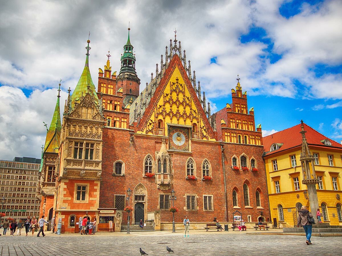 Historisches Altes Rathaus Breslau mit grünen Dächern und belebtem Marktplatz unter bewölktem Himmel in Polen.