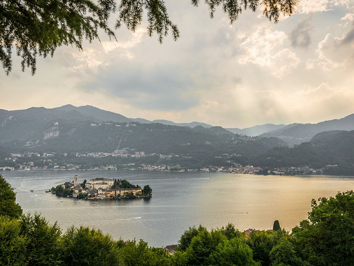 Malerische Insel Isola San Giulio im Ortasee, umgeben von Bergen und Wasser unter bewölktem Himmel.