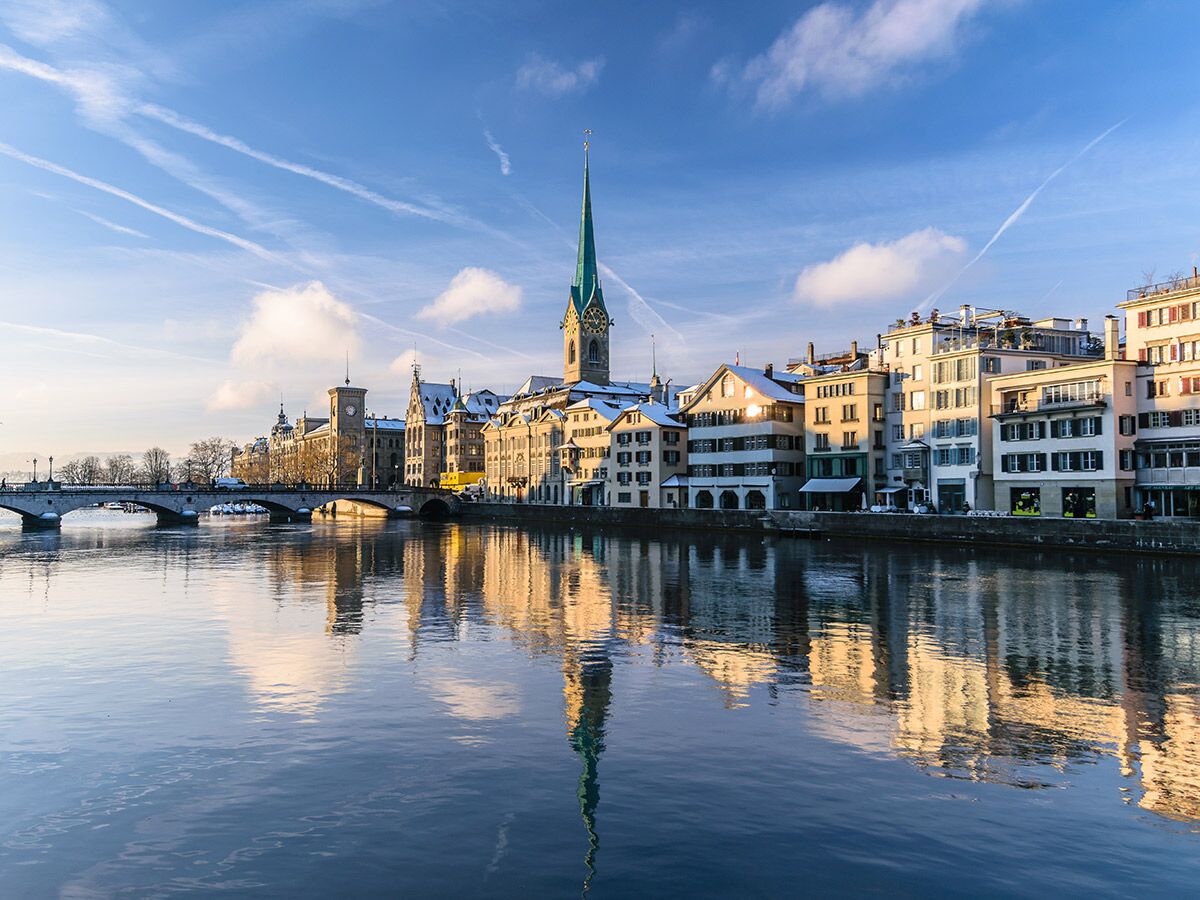 Panoramablick auf Zürich im Winter mit verschneiten Gebäuden am Limmatfluss, Fraumünster-Kirche und Brücken.