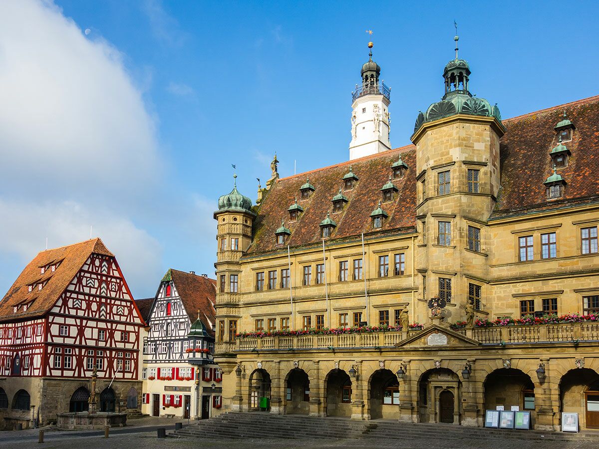 Historischer Marktplatz Rothenburg ob der Tauber mit Fachwerkbauten, Rathaus, Brunnen und Mond am blauen Himmel.
