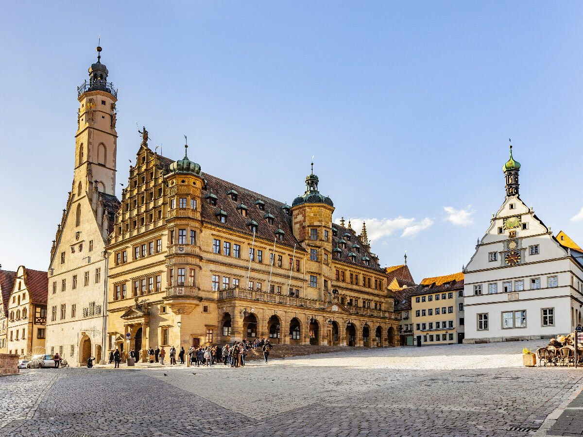 Marktplatz Rothenburg ob der Tauber mit historischem Rathaus, hohem Turm und Ratstrinkstube, belebte Szene an sonnigem Tag.