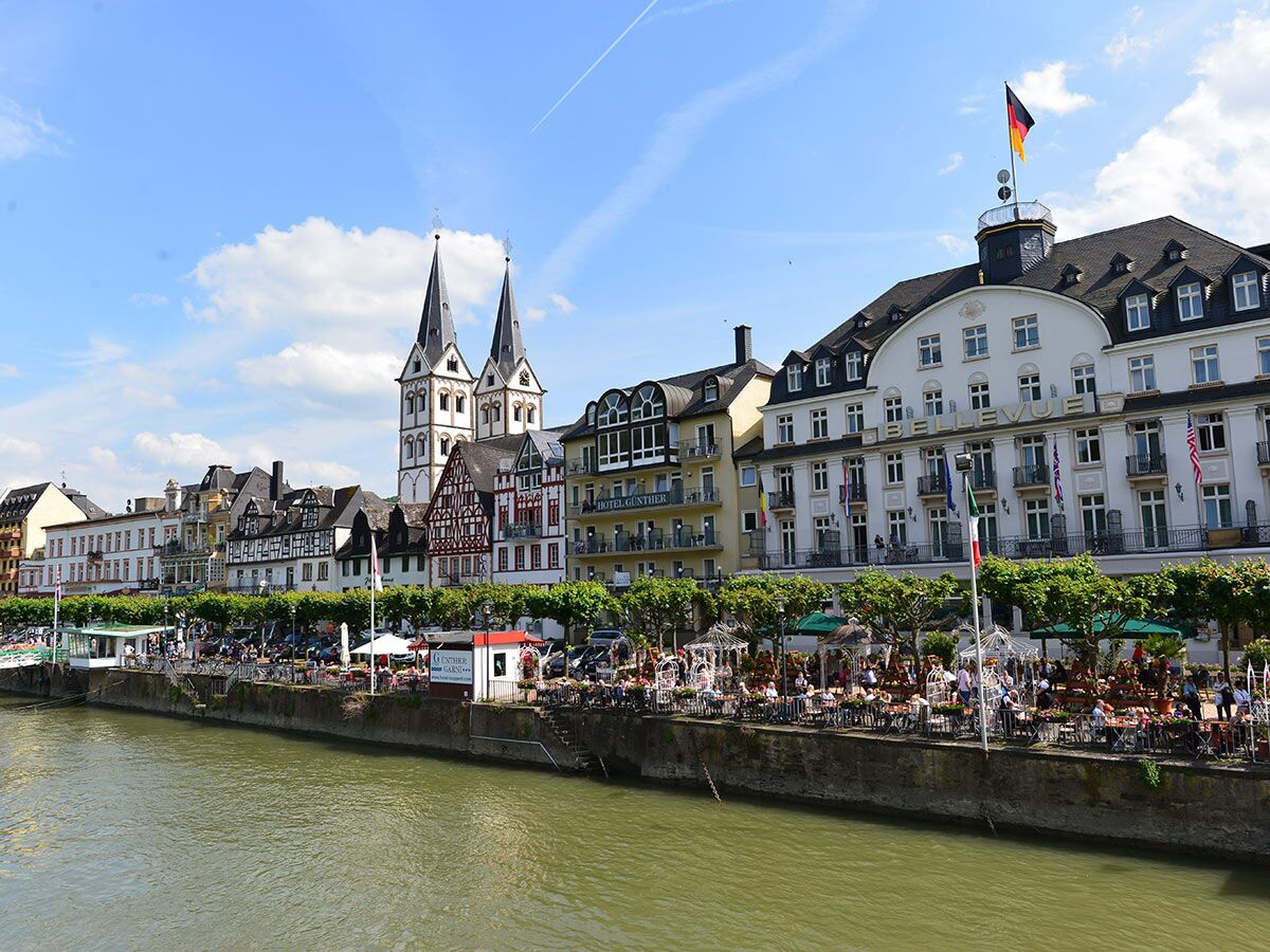 Panoramablick auf die historische Altstadt von Cochem an der Mosel mit der St. Martin Kirche, Hotels und belebten Restaurants am Flussufer.