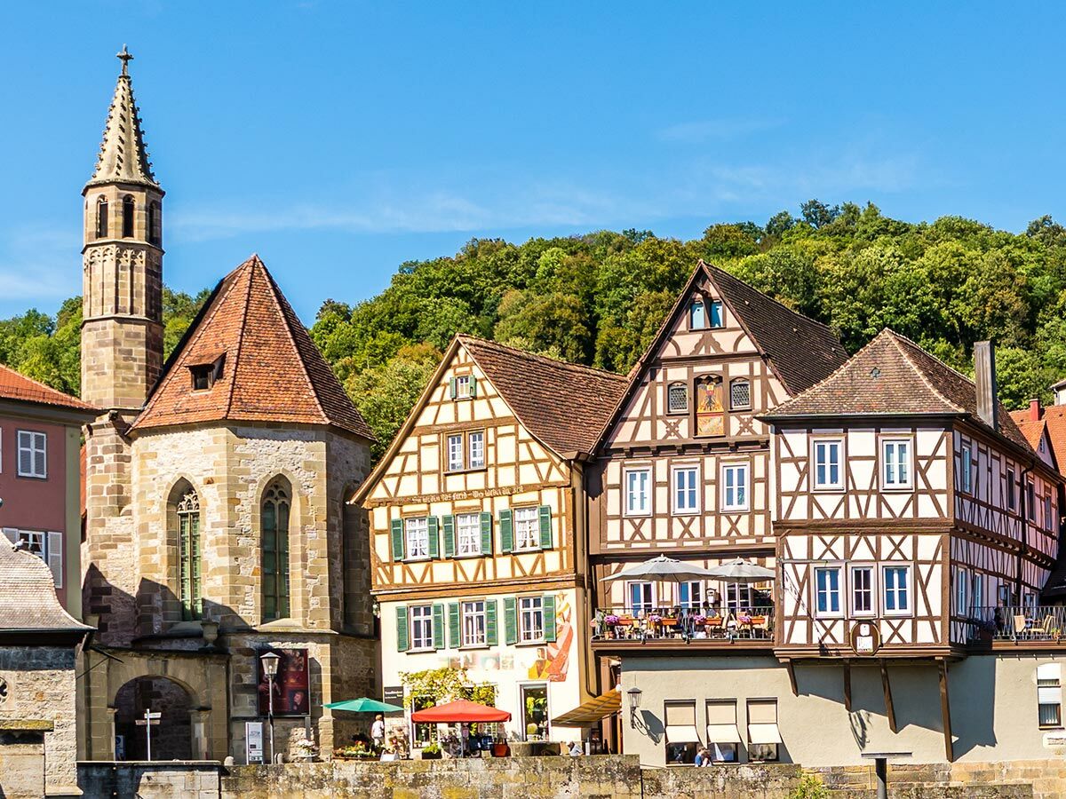 Malerische deutsche Altstadt mit Fachwerkhäusern, Kirche und Turm, grünen Hügeln am Fluss.