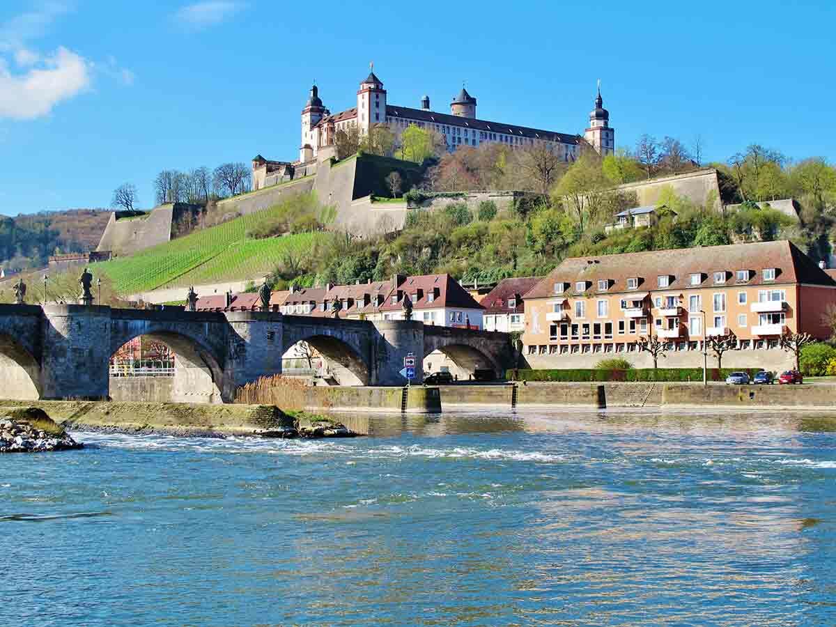 Historisches Panorama von Würzburg mit der Festung Marienberg, der Alten Mainbrücke und dem Fluss Main bei Tag.