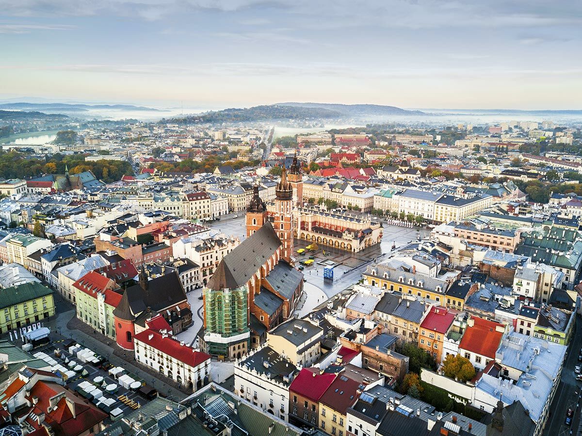 Luftaufnahme von Krakaus Altstadt mit Marienbasilika, Tuchhallen am Hauptmarkt bei nebligem Sonnenaufgang. Historische Gebäude, Dächer.