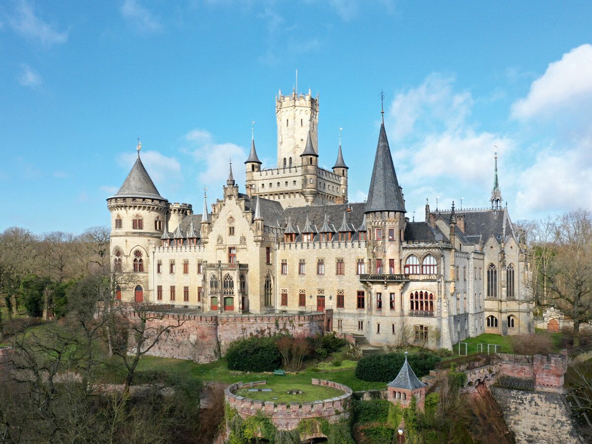Märchenhaftes Marienburg Schloss in Niedersachsen, Deutschland, mit vielen Türmen, spitzen Dächern und romantischer Architektur unter blauem Himmel.