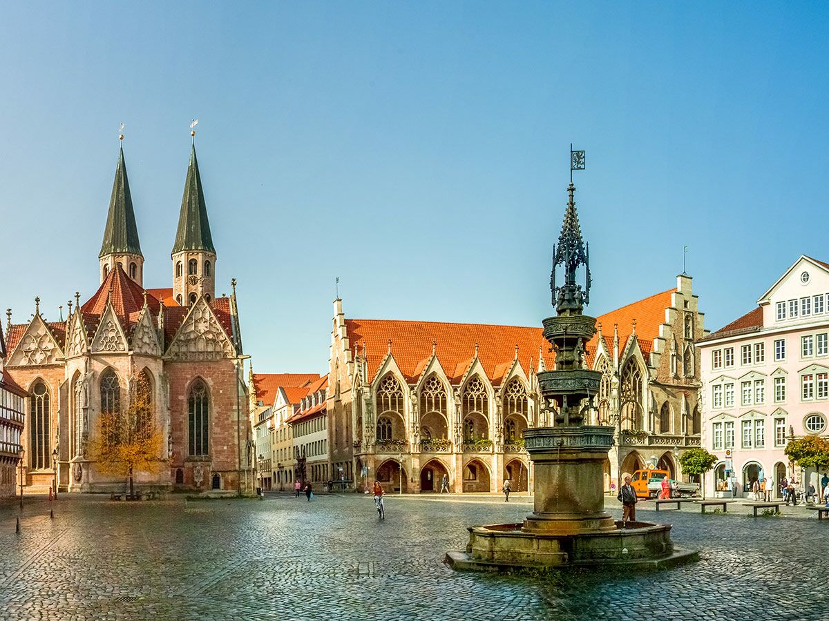 Panoramaansicht des Braunschweiger Altstadtmarktes mit der St. Martini Kirche, dem Altstadtrathaus und dem Marienbrunnen an einem sonnigen Tag.