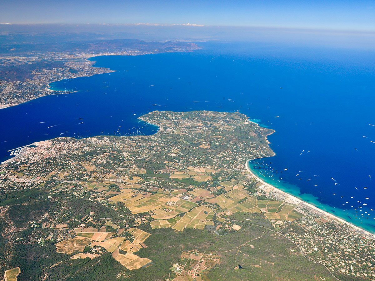 Luftbild der französischen Mittelmeerküste mit dem Golf von Saint-Tropez, Pampelonne Strand, Städten, Booten und Weinbergen unter blauem Himmel.