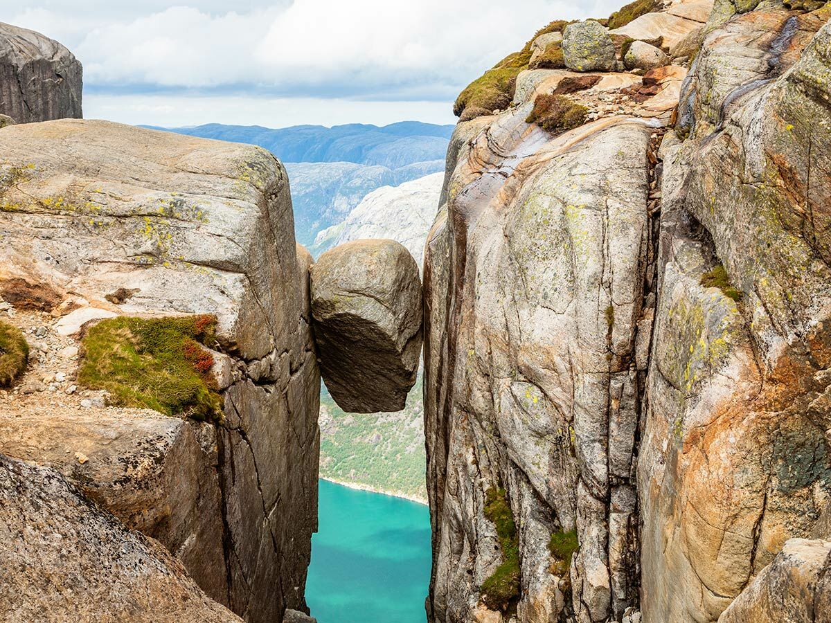 Der ikonische Kjeragbolten, ein riesiger Felsbrocken, der zwischen zwei steilen Felswänden hoch über dem Lysefjord in Norwegen klemmt.