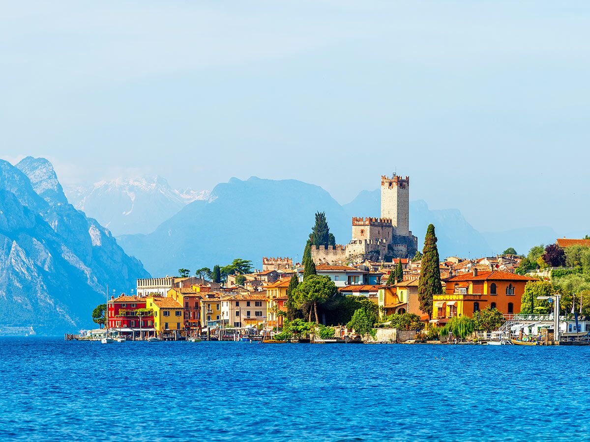 Malerische Stadt Malcesine am Gardasee mit bunten Häusern, Skaligerburg, blauem Wasser und schneebedeckten Bergen.