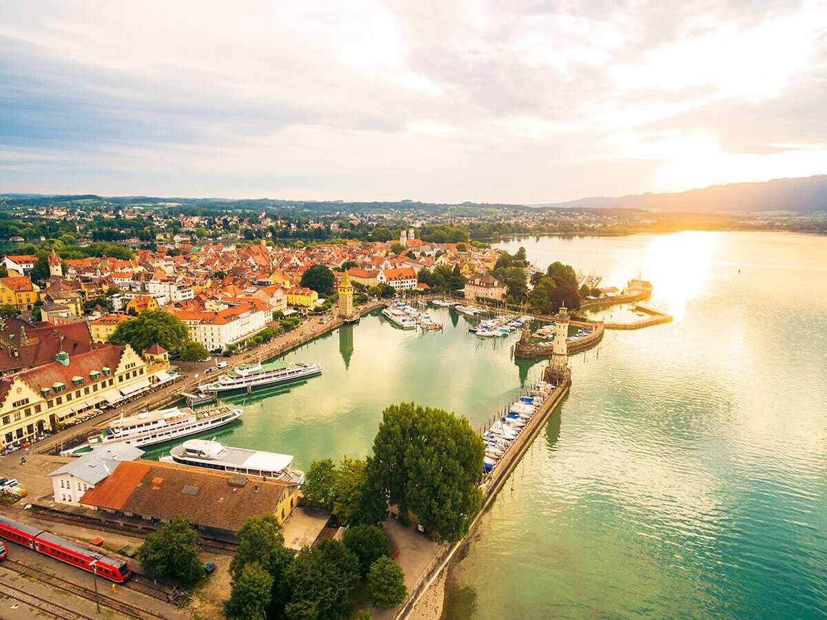 Luftbild von Lindau am Bodensee bei Sonnenuntergang mit historischem Hafen, Leuchtturm, Mangturm und Yachten.