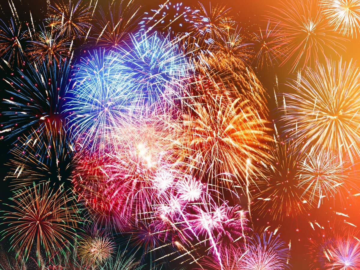 Ein farbenprächtiges Feuerwerk explodiert mit vielen Lichtern am dunklen Nachthimmel, ein festliches Spektakel.