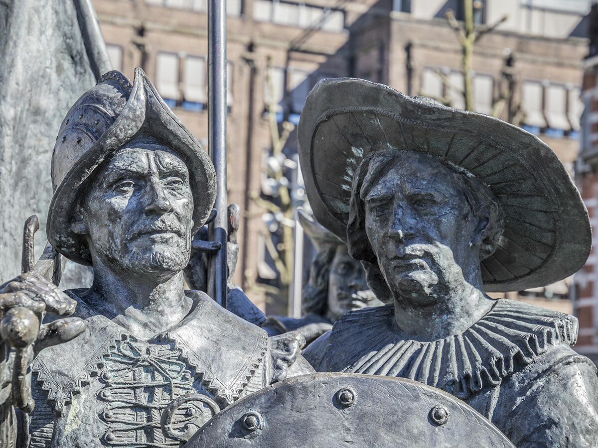 Zwei Bronzestatuen historischer Männer in Rüstung und Kleidung der Epoche, eine mit Helm, die andere mit Hut und Schild.