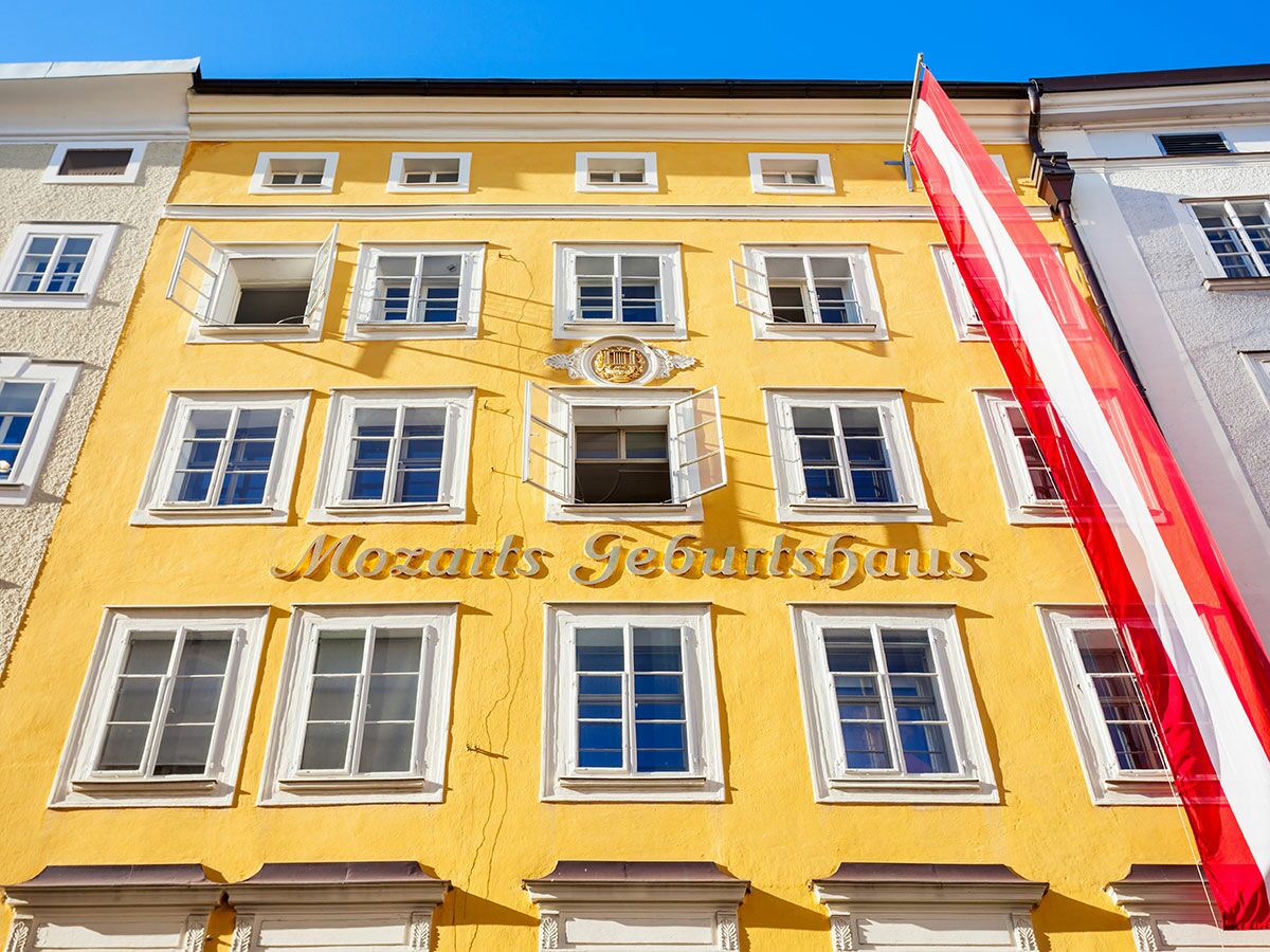 Mozarts Geburtshaus in Salzburg, ein leuchtend gelbes historisches Gebäude mit vielen Fenstern und einer österreichischen Flagge.