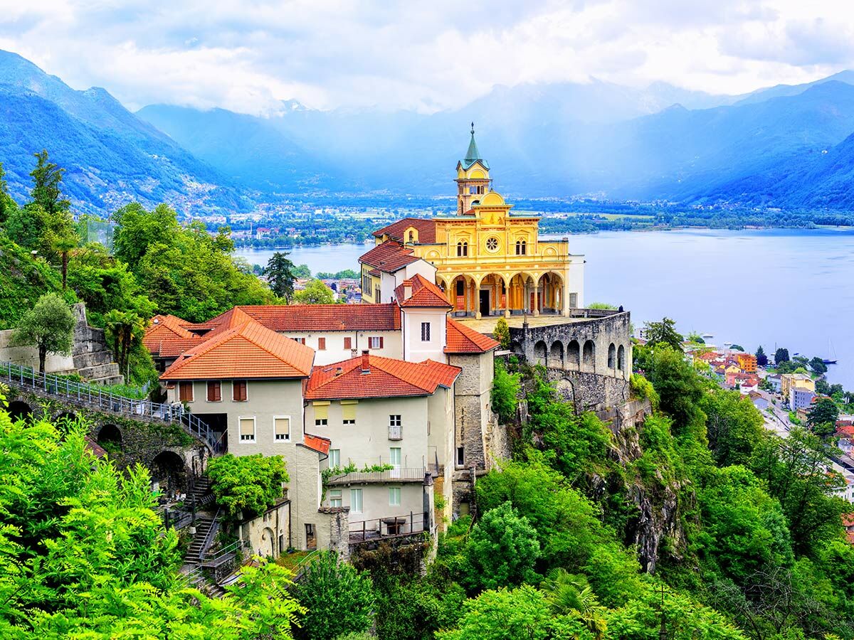 Majestätische Wallfahrtskirche Madonna del Sasso thront über dem Lago Maggiore, umgeben von grünen Hügeln und Bergen.