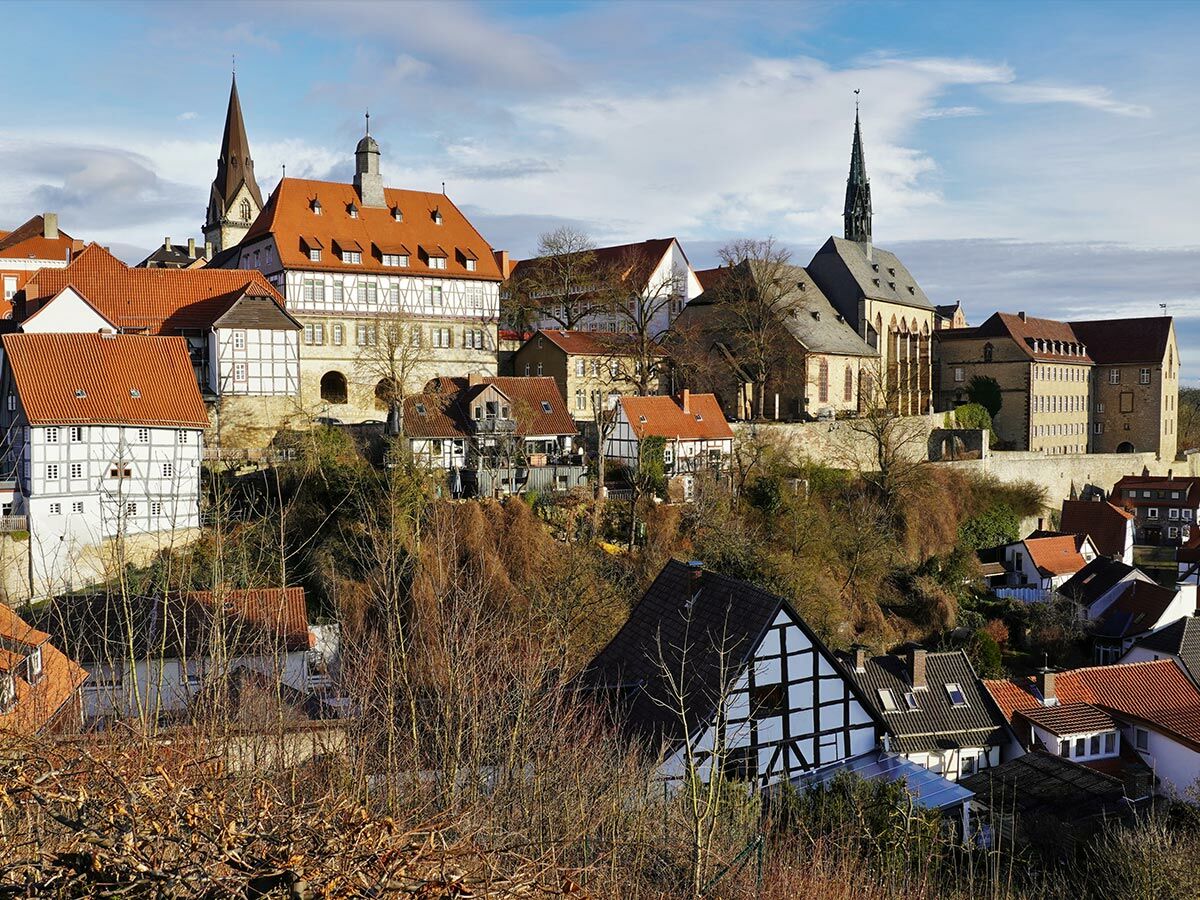 Panorama einer historischen deutschen Stadt mit Fachwerkhäusern, Kirchen, roten Dächern auf einem Hügel im Winter unter blauem Himmel.