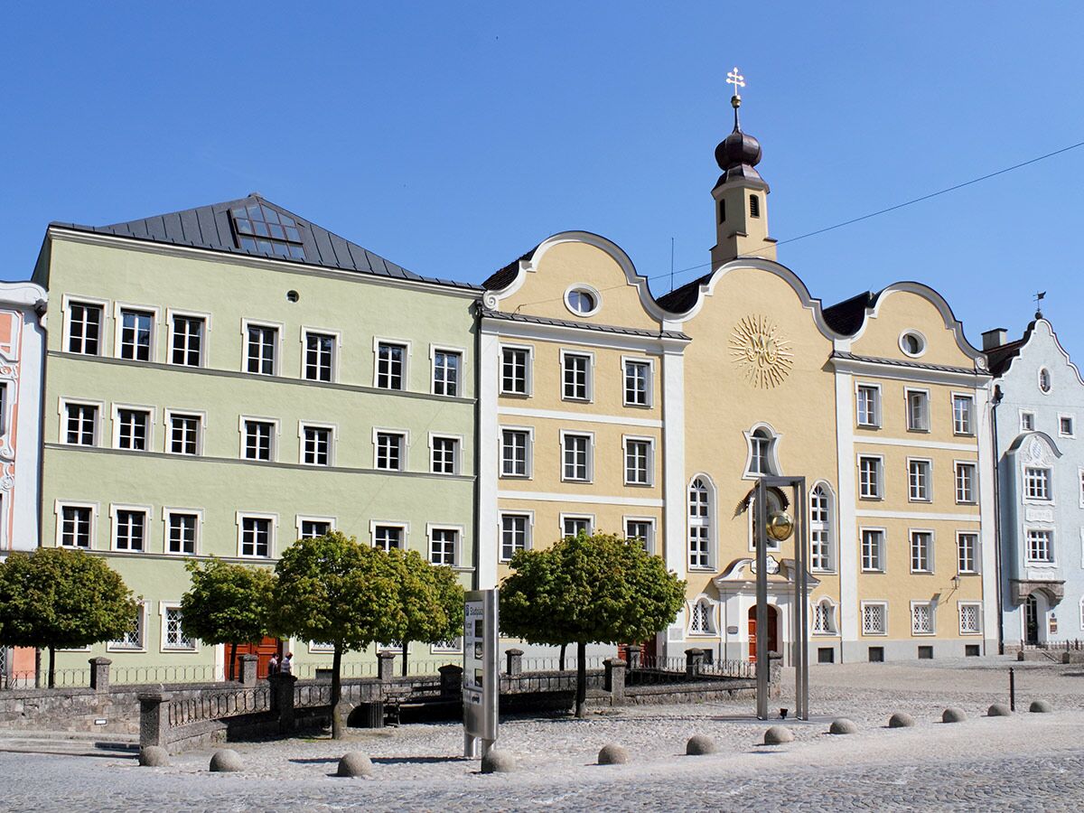 Ansicht des historischen Marienplatzes in Markt Indersdorf mit farbigen Barockgebäuden an einem sonnigen Tag.