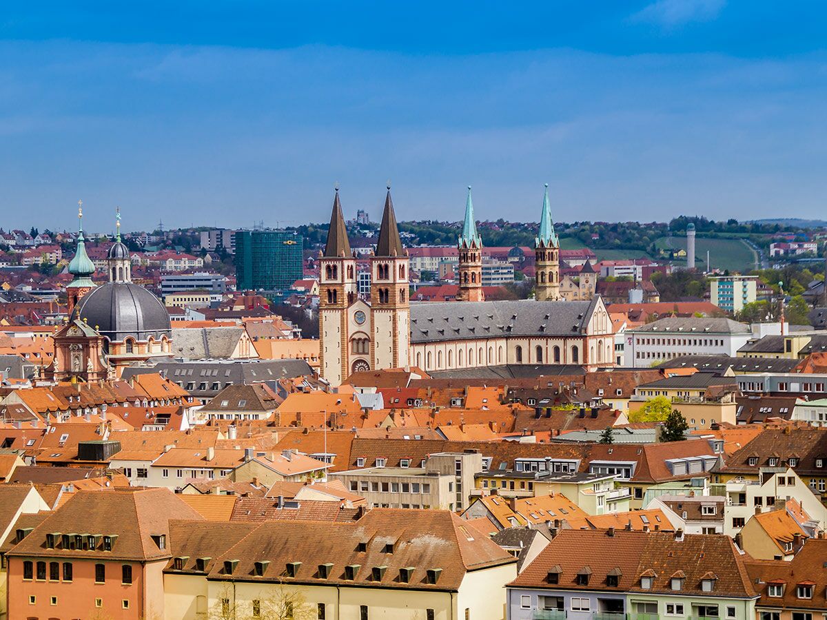 Panoramablick auf Würzburg mit Dom St. Kilian, Neumünster, Marienkapelle und roten Dächern bei blauem Himmel.
