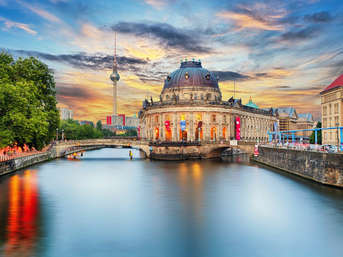 Bode Museum auf der Museumsinsel in Berlin an der Spree bei Sonnenuntergang mit Fernsehturm im Hintergrund.