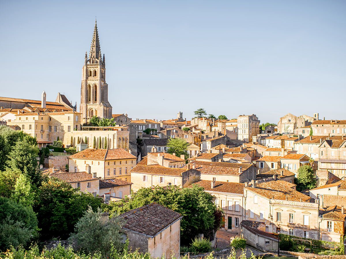 Panoramablick auf die historische Stadt Saint-Émilion in Frankreich mit dem markanten Kirchturm und vielen Dächern unter blauem Himmel.
