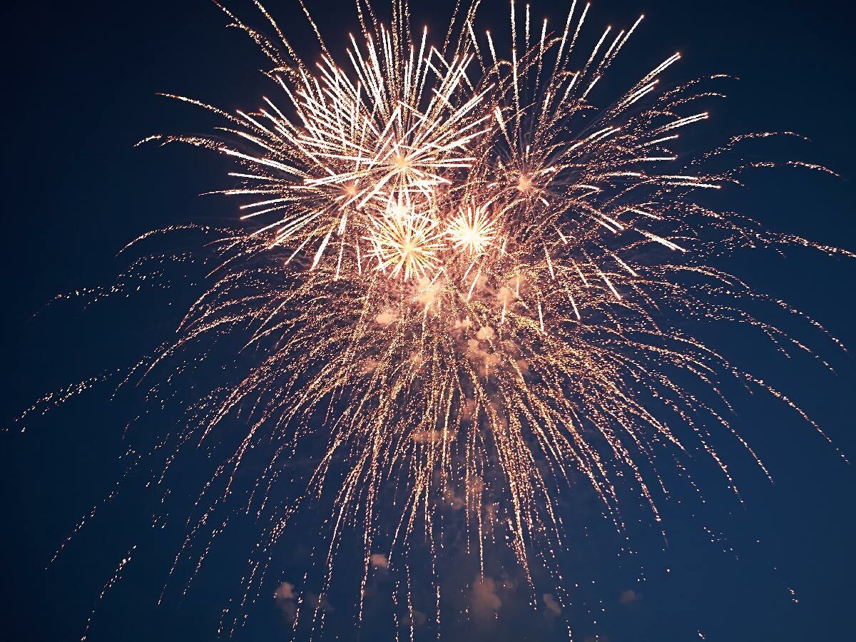 Goldenes Feuerwerk erleuchtet den dunklen Nachthimmel mit zahlreichen Funken und Explosionen bei einer Feier.