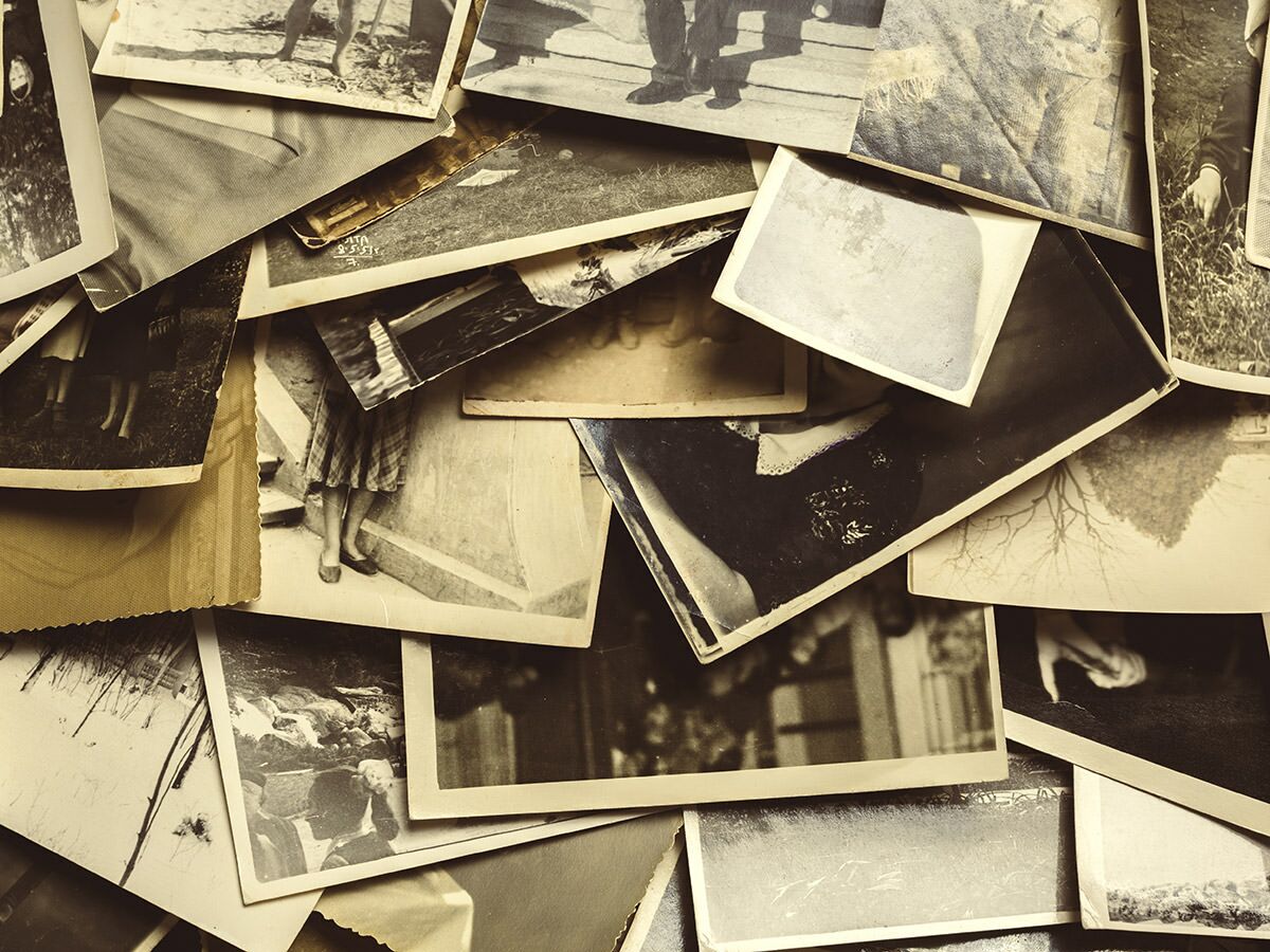Nahaufnahme eines Haufens alter Vintage-Fotos in Sepia-Tönen, die verschiedene Szenen und Personen zeigen.