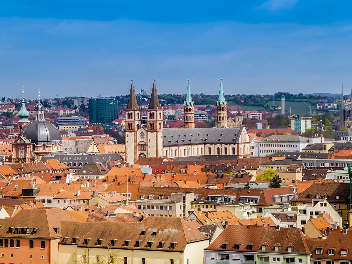 Panoramablick auf die historische Stadt Würzburg mit Dom, Neumünster und roten Dächern unter blauem Himmel.