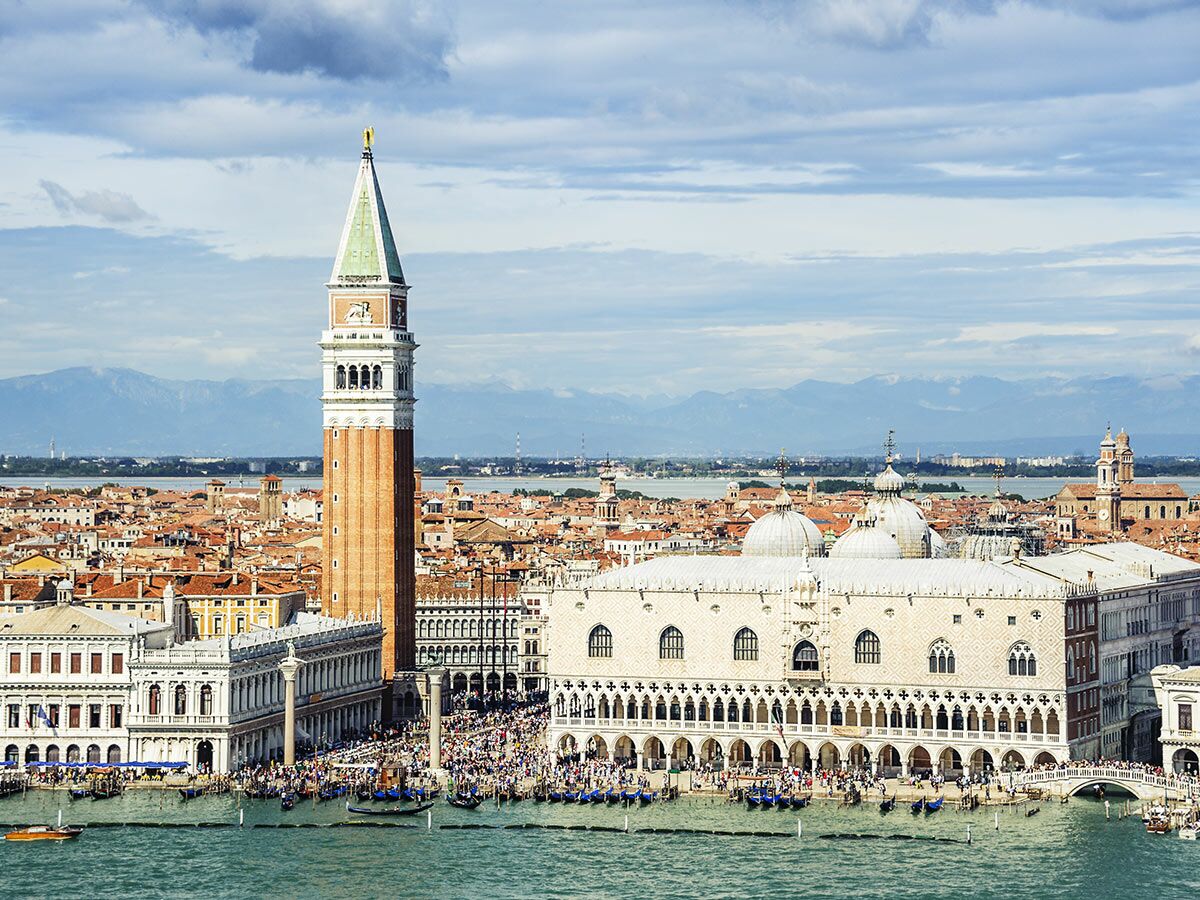 Luftaufnahme von Venedig mit Dogenpalast, Markusplatz, Campanile und Gondeln am Wasser unter bewölktem Himmel.