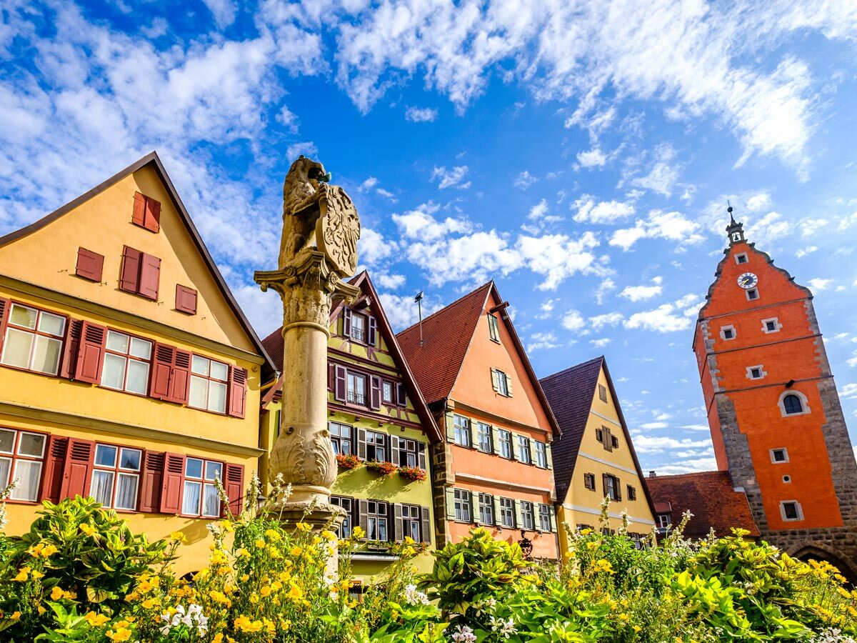 Blick auf die historische Altstadt von Rothenburg ob der Tauber mit bunten Häusern, Löwenbrunnen und Uhrturm.