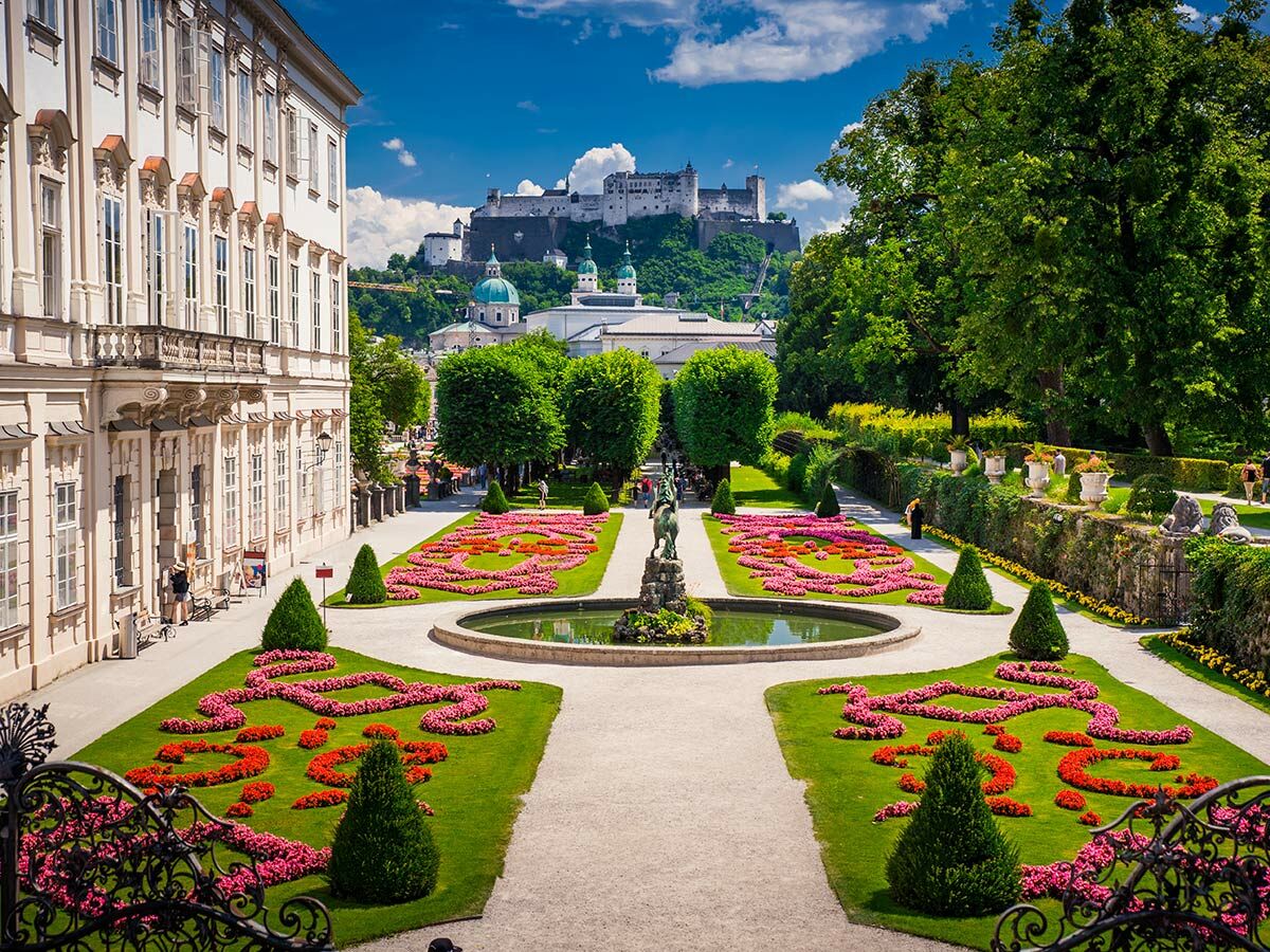 Blick auf den Mirabellgarten Salzburg mit Schloss Mirabell, bunten Blumenbeeten, Springbrunnen und Festung Hohensalzburg.