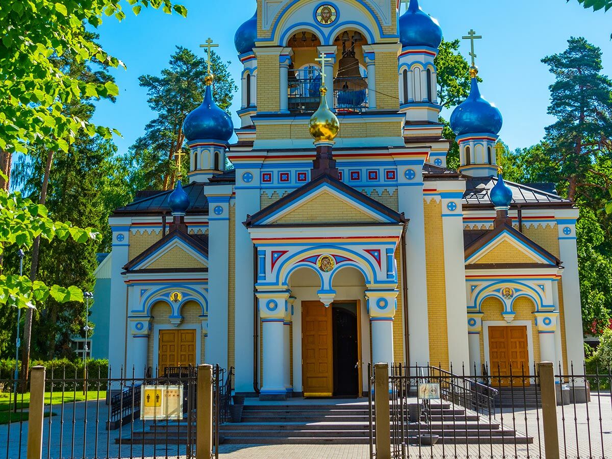 Prachtvolle orthodoxe Kirche mit blauen und goldener Kuppel, gelben Ziegeln, bunten Verzierungen unter blauem Himmel.