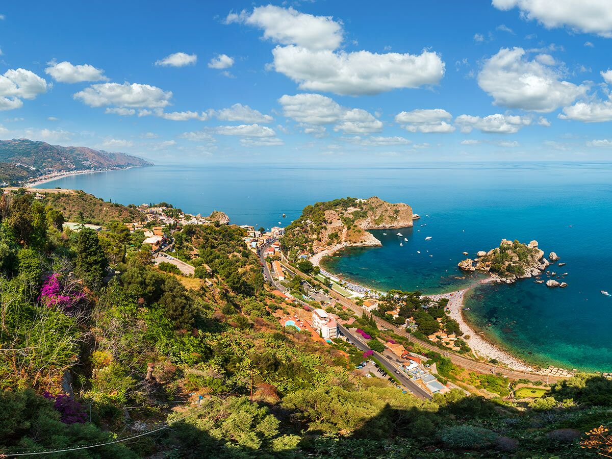 Panoramablick auf Isola Bella, die Küste von Taormina und das türkisfarbene Meer unter blauem Himmel mit weißen Wolken.