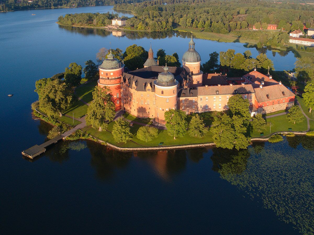 Luftaufnahme von Gripsholm Schloss auf einer Insel im See Mälaren, Schweden, umgeben von Bäumen und Wasser.