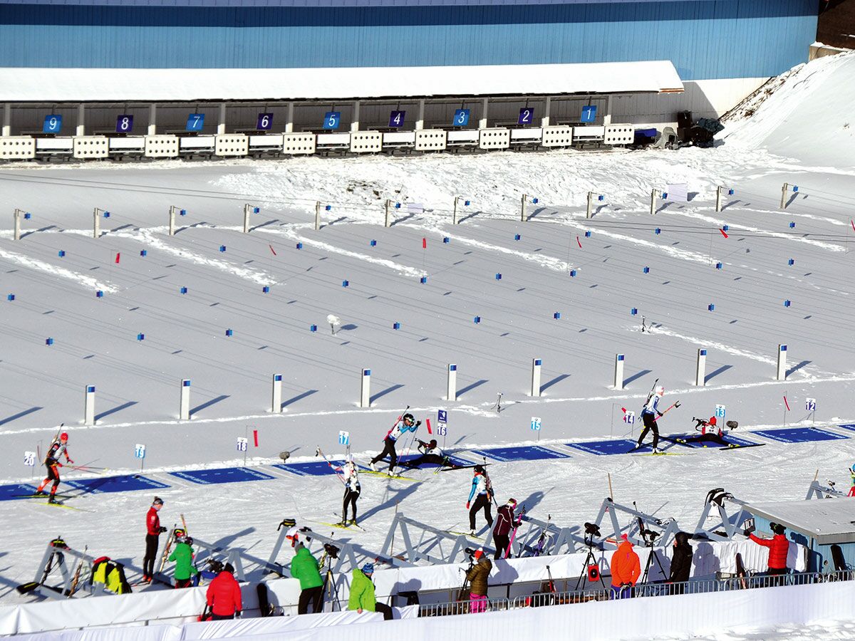 Hochwinkelaufnahme eines Biathlon-Wettkampfs mit Sportlern beim Skifahren und Schießen auf die Zielscheiben im Schnee. Winter, Sport.