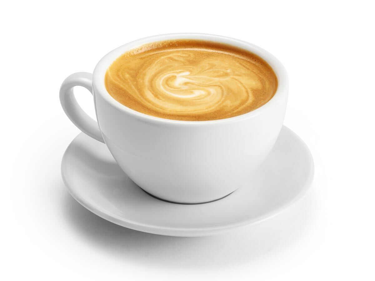 Eine weiße Kaffeetasse mit Cappuccino, verziert mit cremiger Latte Art in einem Wirbelmuster, auf weißer Untertasse.