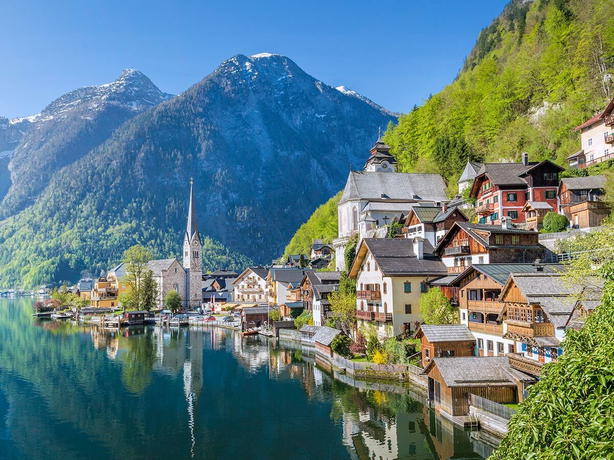 Panoramablick auf Hallstatt, Österreich, mit seiner Kirche, bunten Häusern am Seeufer und schneebedeckten Alpen im Hintergrund.
