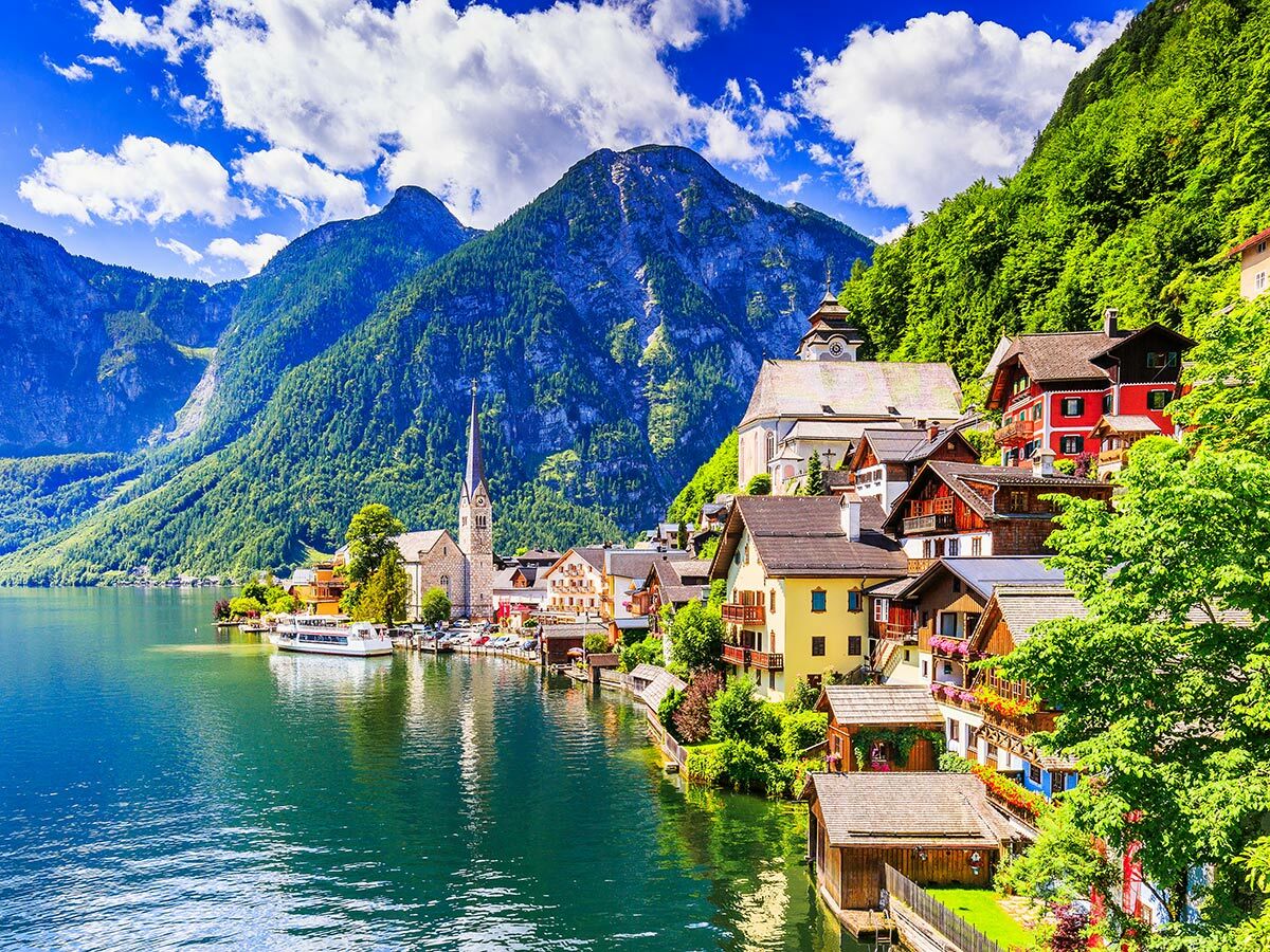 Panoramablick auf das idyllische Dorf Hallstatt am Hallstätter See mit historischen Häusern, Kirche und majestätischen Bergen.