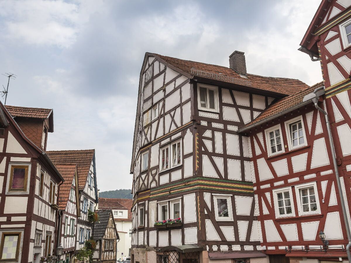 Malerische Gasse mit historischen Fachwerkhäusern und roten Ziegeldächern unter bewölktem Himmel in Deutschland.