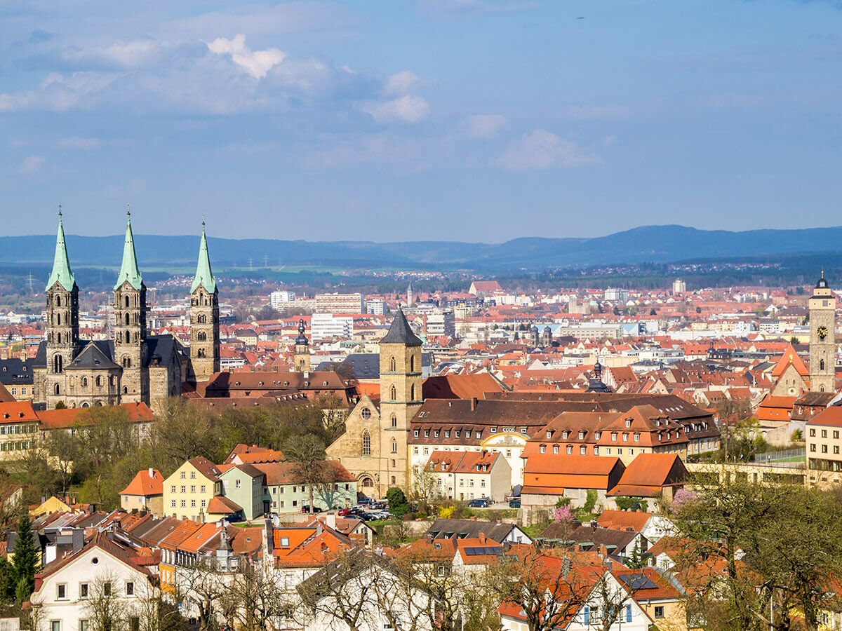 Panoramablick auf Bamberg mit Dom, Altstadt und roten Dächern unter blauem Himmel.