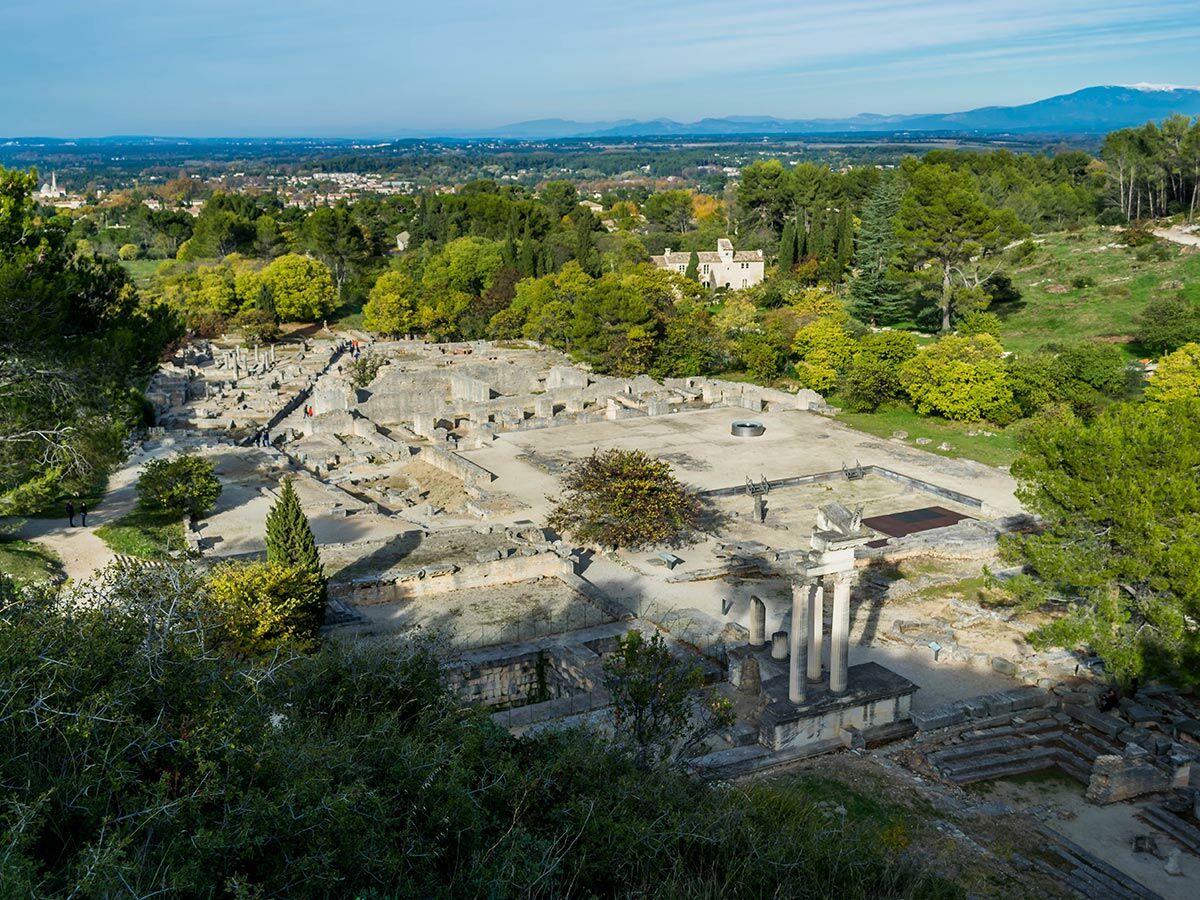 Panoramablick auf die weitläufige römische Ausgrabungsstätte in Vaison-la-Romaine, Frankreich, mit antiken Ruinen, Säulen und Besuchern.