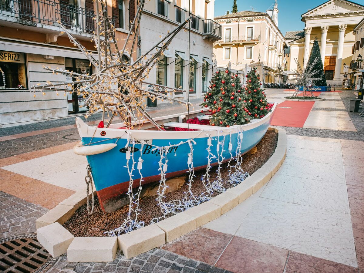Blaues Boot als Weihnachtsdekoration im Stadtzentrum mit geschmückten Bäumen und Lichtern, festliche Winterstimmung.