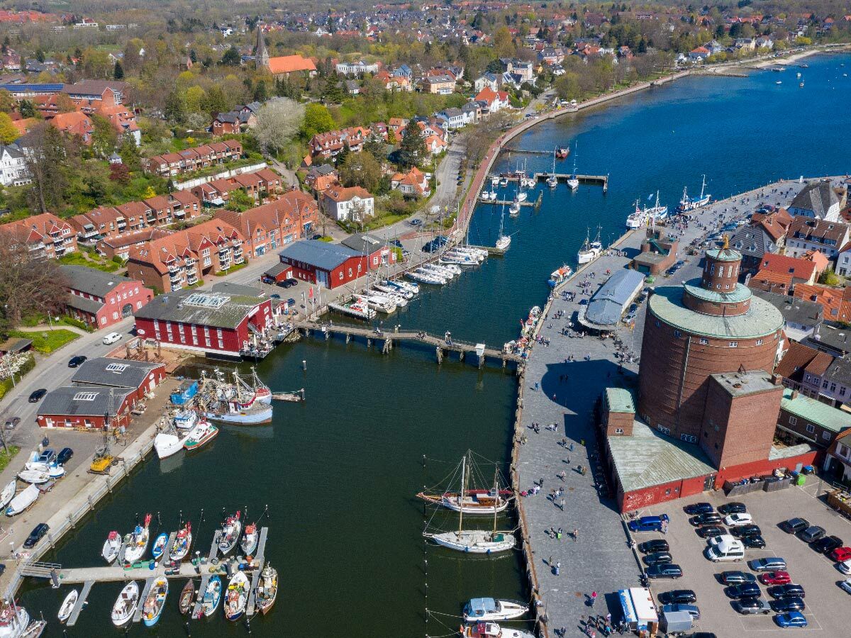 Luftaufnahme des historischen Hafens von Flensburg mit roten Gebäuden, Booten, Promenade und parkenden Autos. Idyllische Hafenstadt an der Förde.