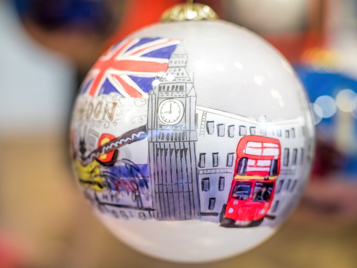 Nahaufnahme einer weißen Weihnachtskugel mit Illustrationen von Londoner Wahrzeichen wie Big Ben, Doppeldeckerbus und Union Jack.